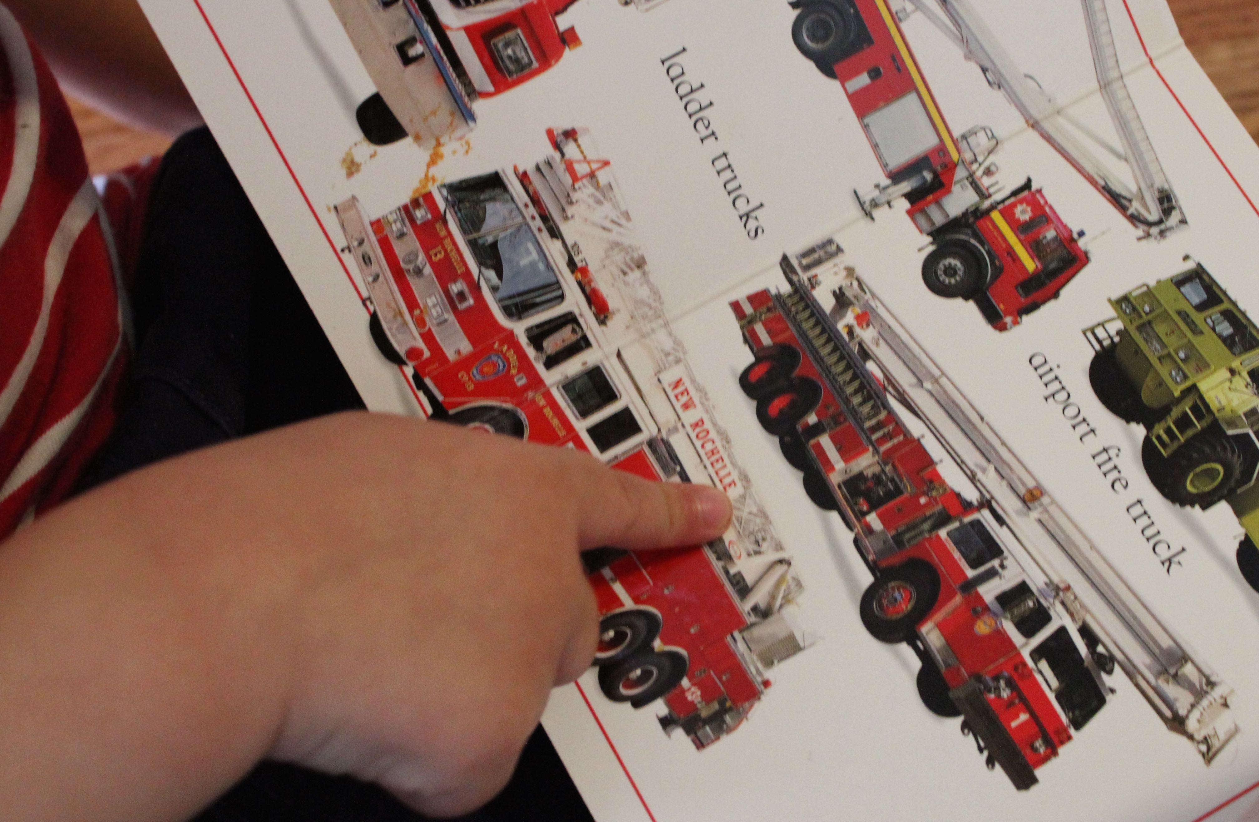 Luke points to or 'tacts' all the fire trucks on the page.
